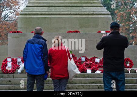 Southampton, UK, 8 Nov, 2020.  Remembrance Sunday 2020 input - Commemoration service held at the Cenotaph in Southampton, UK  Pictured: A couple pay their respects and a man takes a photograph of poppy wreaths that have been placed at the base of the Cenotaph in Southampton this morning, Sunday November 8, 2020.  A large public service was held at the Cenotaph in Southampton, UK, Sunday November 8, 2020.  The pandemic and second national lockdown in England has meant that many local councils have had to alter commemoration plans this year, encouraging residents to participate from the safety o Stock Photo