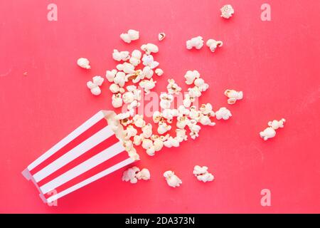 popcorn spilling from a container on red background  Stock Photo