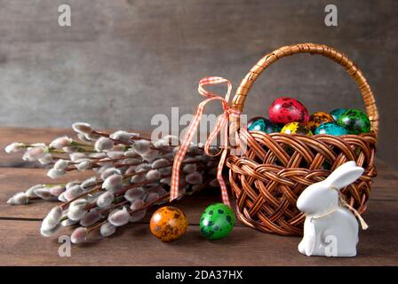 Wicker basket with Easter eggs and willow twigs bouquet Stock Photo