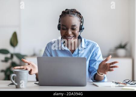 Web Conference. Black Female Employee In Headset Making Video Call With Laptop Stock Photo