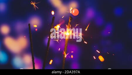 Photos on a bright blue purple background with sparklers festive lights holiday and Christmas and New Year on the desktop or banner on the website Stock Photo