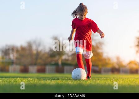 Girl kicks a soccer ball on a soccer field Stock Photo