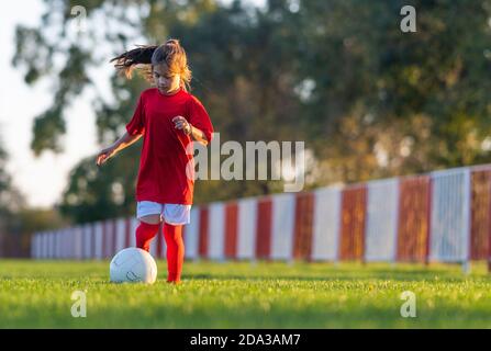 Girl kicks a soccer ball on a soccer field Stock Photo