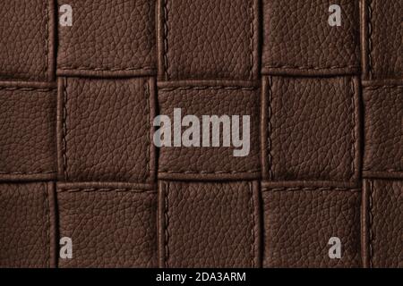 Texture of dark brown leather background with square pattern and stitch, macro. Abstract backdrop from modern decorative umber textile with geometric Stock Photo