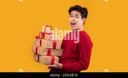 Happy asian man holding stack of present boxes Stock Photo