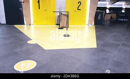Yellow round sign printed on ground at supermarket cash desk register informing people to keep 2 meter 6 feet distance from each other to prevent