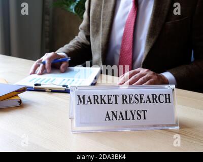 Market research analyst plate on the desk and worker. Stock Photo