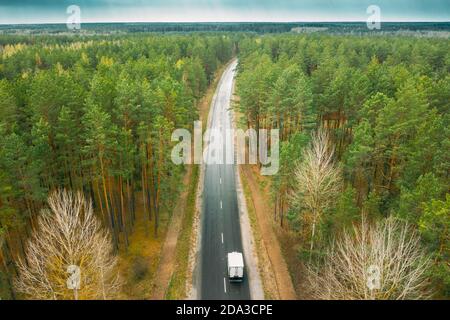 Aerial View Of Highway Road Through Spring Forest Landscape. Top View Of Truck Tractor Unit Prime Mover Traction Unit In Motion On Freeway. Business Stock Photo
