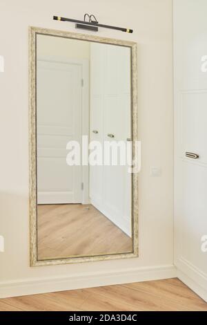 Large interior mirror in vintage white bronze wooden frame on wall Stock Photo