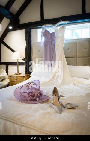 Wedding dress and mother of the bride dress hanging in a hotel bedroom. Stock Photo