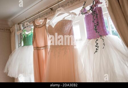 Bride's wedding dress and bridesmaid dresses hanging at a bedroom window. Stock Photo