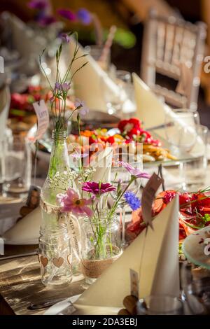 Flowers in glass jam jars on a table at a wedding reception. Stock Photo