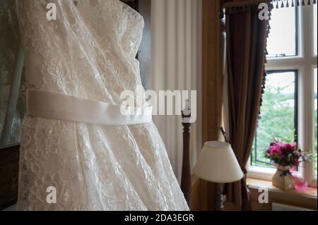 Close up of  beautiful white wedding dress hanging up in a bedroom before the wedding. Stock Photo