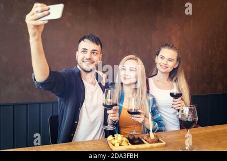 Happy young friends taking selfie drinking wine at restaurant Stock Photo