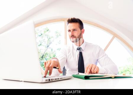 Handsome businessman looking thoughtfully while working at office desk in the office. Stock Photo