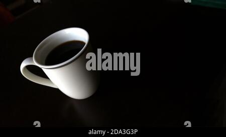 Angled white mug with black coffee on black background Stock Photo