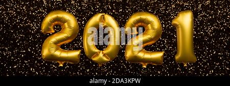 2021 written with golden balloons floating on gold glitter panoramaic background, new year party web banner Stock Photo