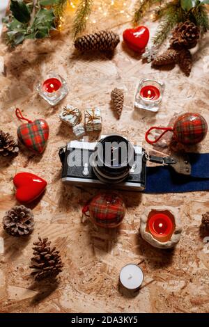 Christmas still life with a classic vintage camera, tree decorations, little gifs, red candles and pinecones Stock Photo