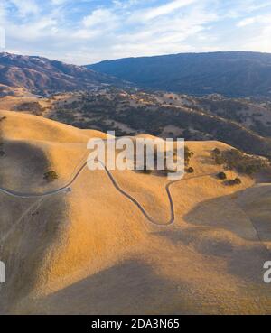 Golden sunlight shines on the rolling hills in Northern California. These beautiful, eroded hills turn green once winter brings seasonal rain. Stock Photo