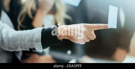 close up. employees discussing a sticky note on the glass Stock Photo