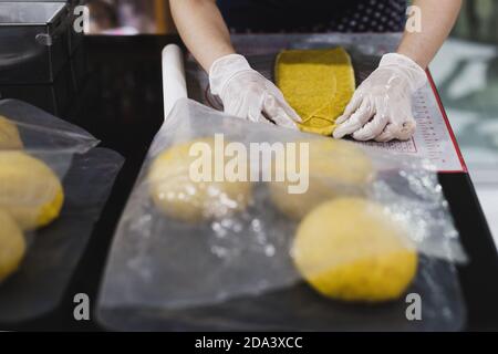 Womens hands roll out the pumpkin bread dough on kitchen table. Stock Photo