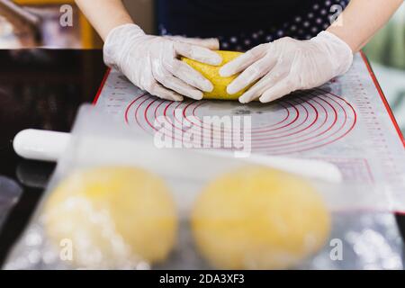 Womens hands roll out the pumpkin bread dough on kitchen table. Stock Photo