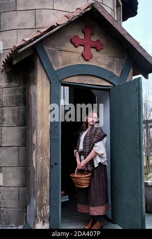 Parishioner at the entrance to the retro Church with a large red cross over the door. Retro clothes on Halloween in style 18-19th century Stock Photo