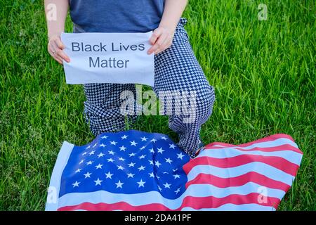 Woman kneeling 'black lives matter' signs during a rally to speak about the plurality of violence and anti-Black racism - New York, USA, June 11, 2020 Stock Photo