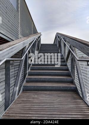 Stairs with stainless steel hand railings and wooden steps. Staircase with the sky in the background. Stairs with steps up. Stock Photo