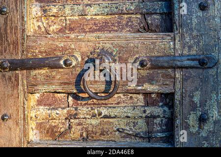 Ancient old metal door handle knocker on a wooden door. Close up Stock Photo