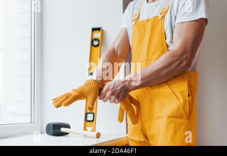 Handyman in yellow uniform preparing for work indoors. House renovation conception Stock Photo