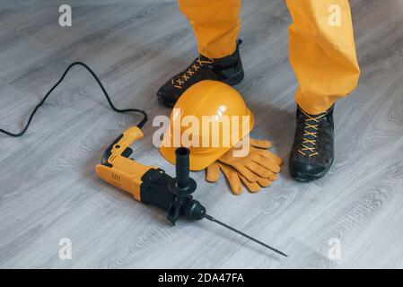 Handyman in yellow uniform with drill standing indoors. House renovation conception Stock Photo