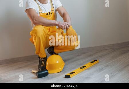 Tools on the floor. Handyman in yellow uniform standing indoors. House renovation conception Stock Photo