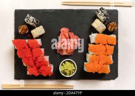 A set of colorful sushi set on a white table with wine in a cozy room. Stock Photo