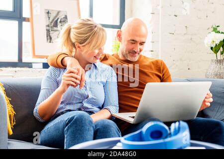 Shot of a happy couple using a laptop while relaxing on the sofa at home. Stock Photo
