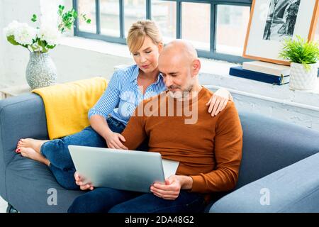 Shot of a happy couple using a laptop while relaxing on the sofa at home. Stock Photo