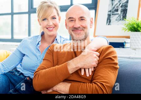 Shot of happy couple sitting on couch at home and bonding to each other while relaxing at home. Stock Photo
