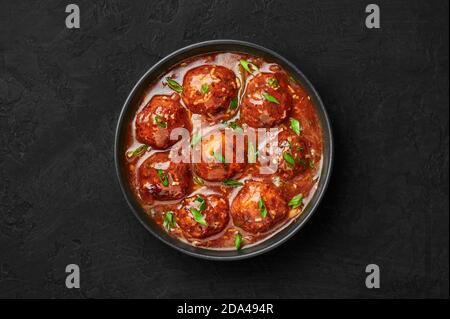 Veg Manchurian Gravy Balls in black bowl in dark slate table top. Vegetarian Manchurian is indian chinese cuisine dish. Asian food and meal. Top view Stock Photo