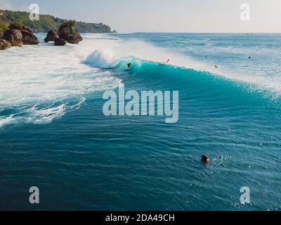 Aerial view with surfing at barrel wave. Blue perfect waves and surfers in ocean Stock Photo