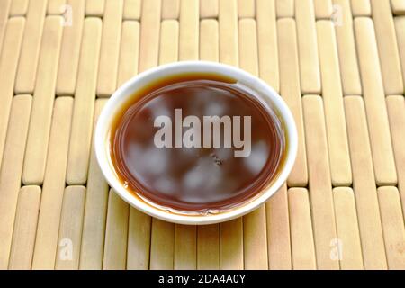 black soybean sauce in little cup on bamboo plate Stock Photo