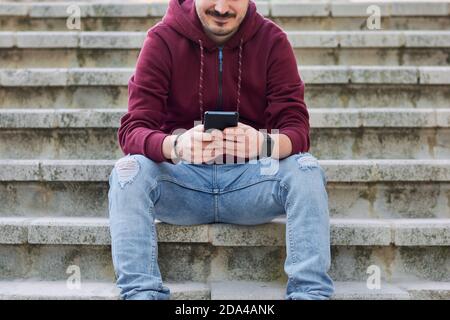 Unrecognizable man types on his cell phone Stock Photo