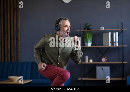 Excited senior handsome man celebrating victory holding smartphone. Big success, great achievements, positive emotions. Victory dance, good deal Stock Photo