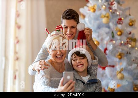 Mother and sons taking selfie at a Christmas party at home Stock Photo