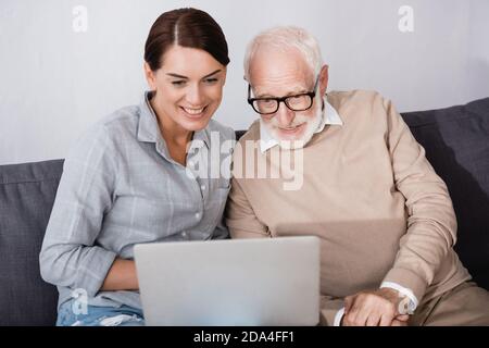 smiling woman with concentrated father using laptop together at home Stock Photo