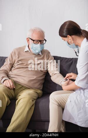 collage of geriatric nurse examining aged man with a stethoscope at home Stock Photo