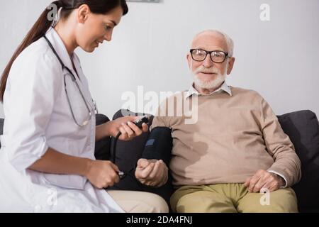 collage of geriatric nurse examining aged man with tonometer at home Stock Photo