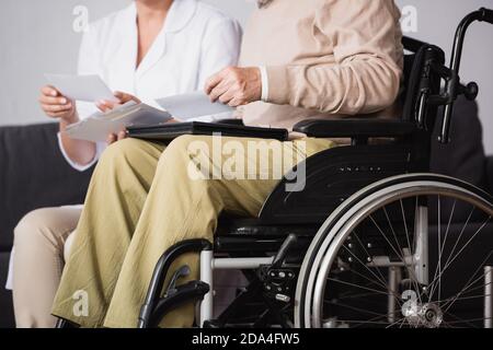 cropped view of social worker showing family photos to handicapped man on blurred background Stock Photo