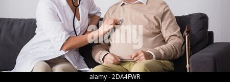cropped view of nurse examining aged man with stethoscope, banner Stock Photo