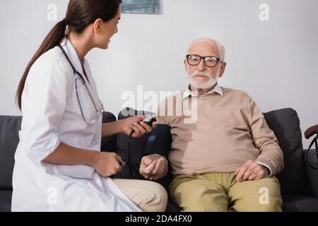 brunette geriatric nurse examining elderly man with stethoscope Stock Photo