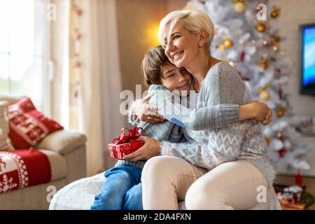 Smiling boy receiving gift from his mother at Christmas Stock Photo